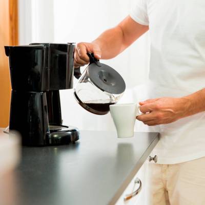 Man in the kitchen pouring a mug of hot filtered coffee from a g